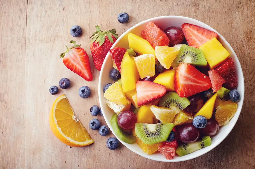 A bowl of the lowest calories fruit. A selection of kiwis, oranges, mango, strawberries, blueberries and grapes
